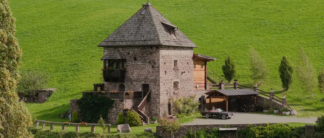 Wohnturm des Stofnerhofs auf einer Wiese über Sarnthein, aus der Luft gefilmt